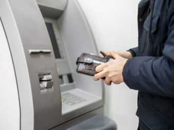 persons hand hold a wallet with cash and withdraw some money in atm
